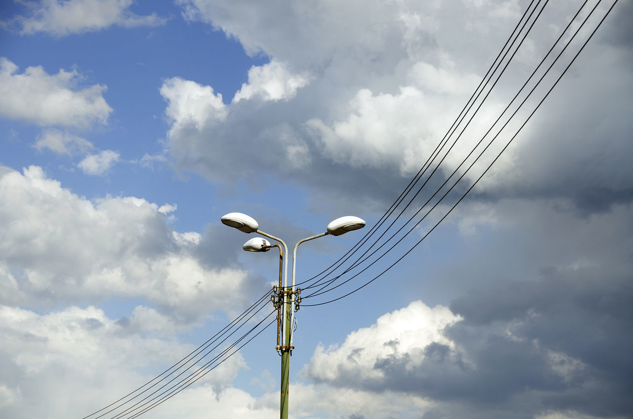 Low angle view of power lines against cloudy sky
