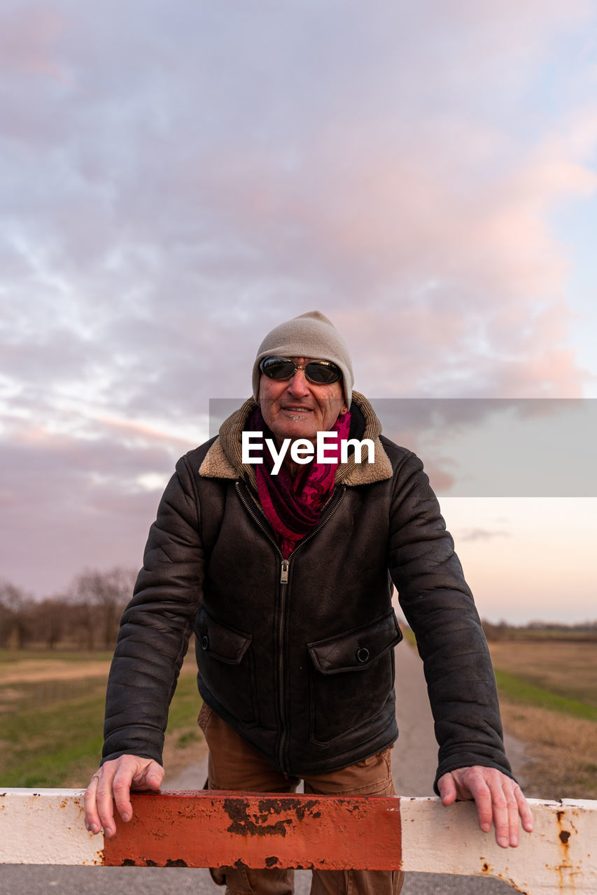 Middle aged man wearing winter clothes taking a break in a country road - people in recreation