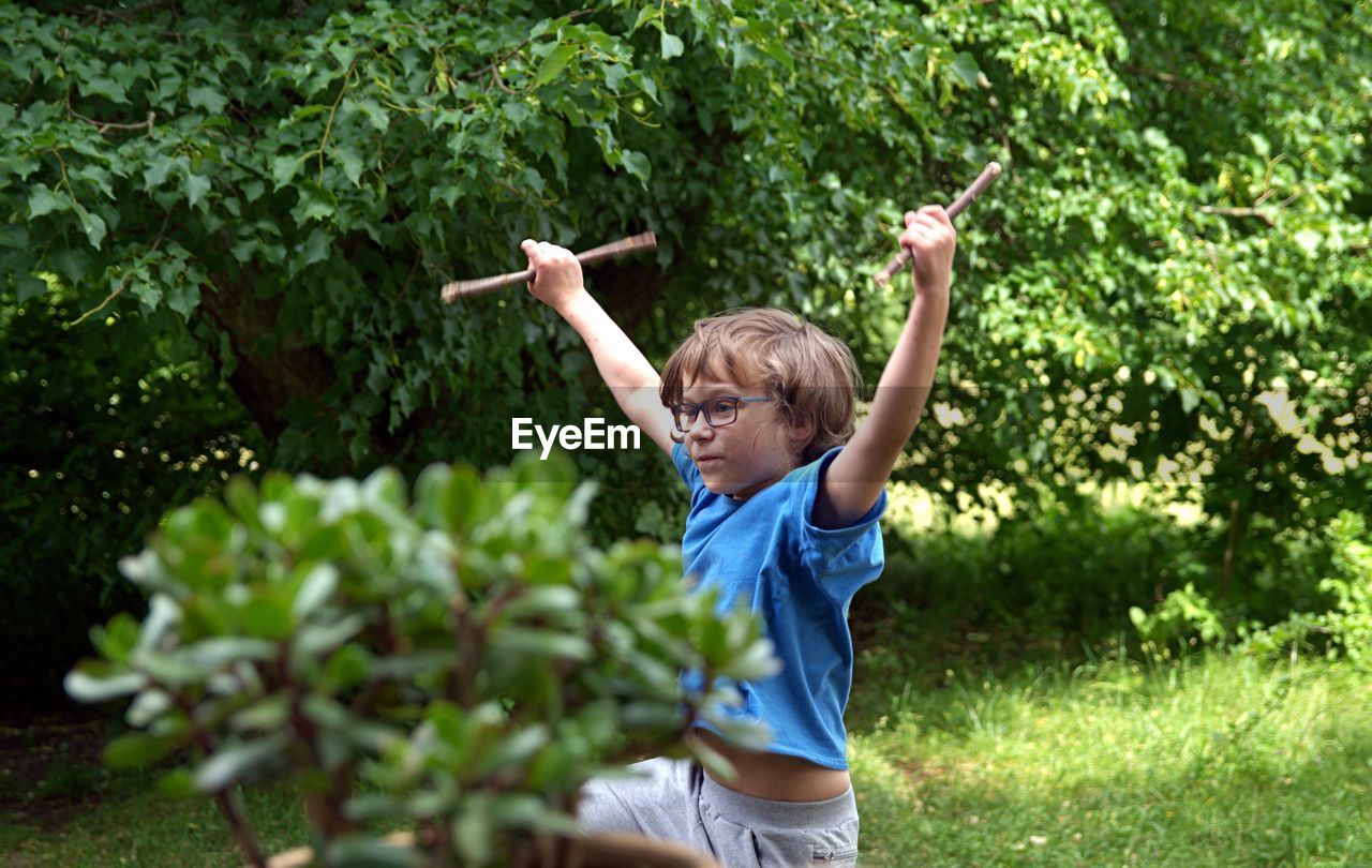 Boy holding sticks while dancing in park