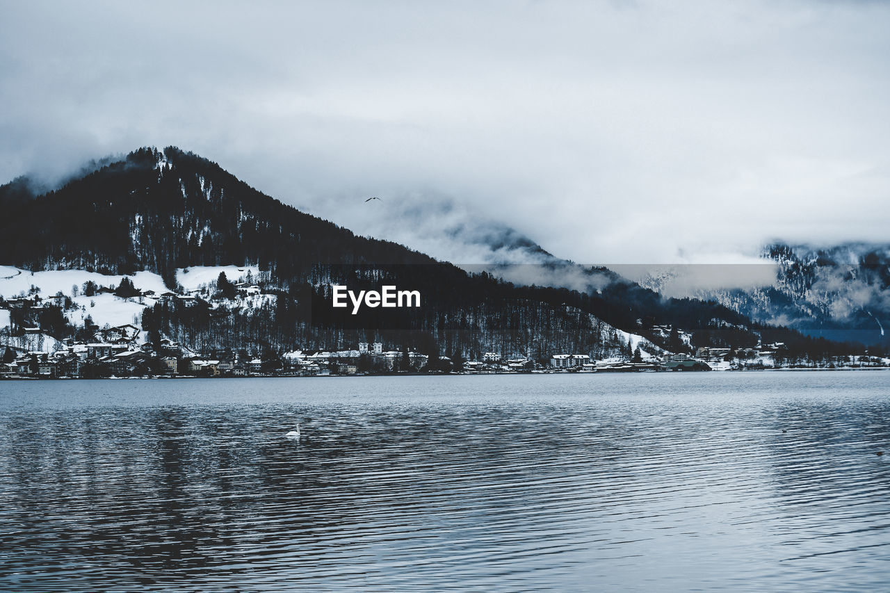 Scenic view of sea by snowcapped mountain against sky