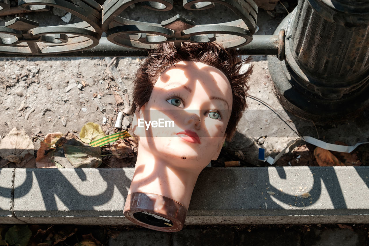 High angle view of female mannequin head on footpath