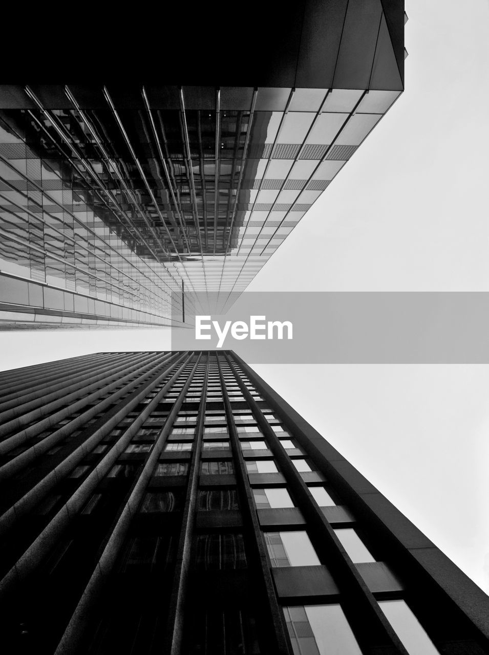 LOW ANGLE VIEW OF MODERN GLASS BUILDING AGAINST SKY