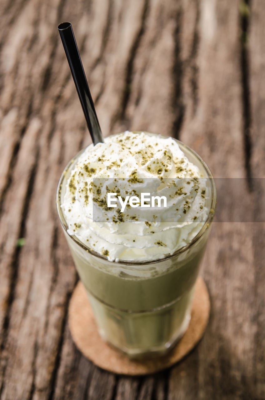 High angle view of milkshake with whipped cream in glass on table