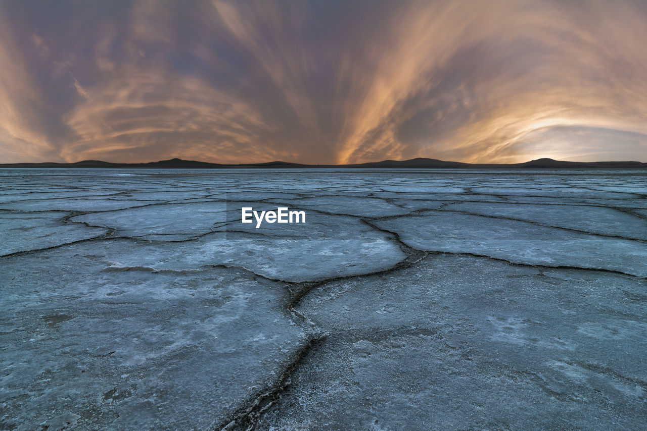 Amazing scenery of salty lagoon with dried rough ground under sundown sky in penahueca