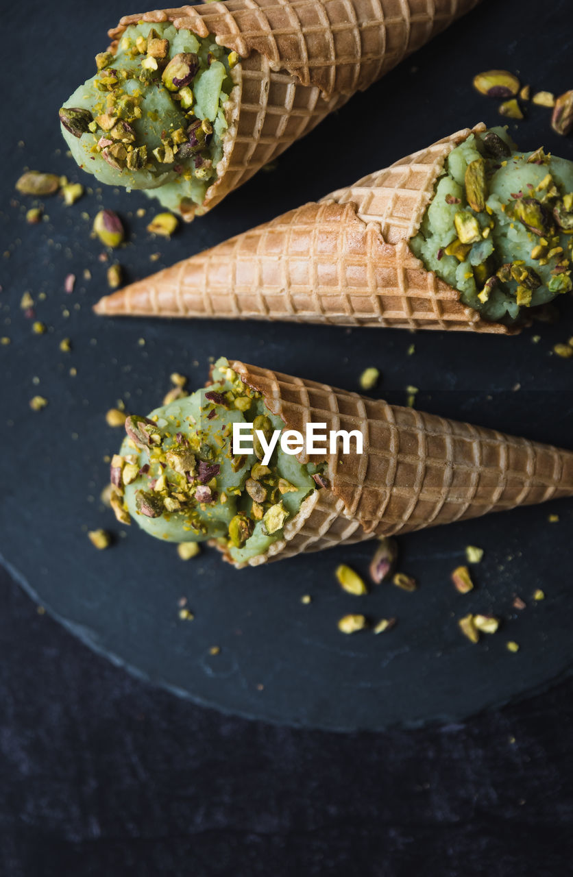 Close up of pistachio ice cream in cones on black background.