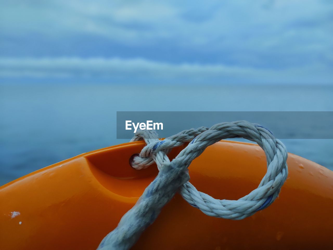 Close-up of rope tied on sea against sky