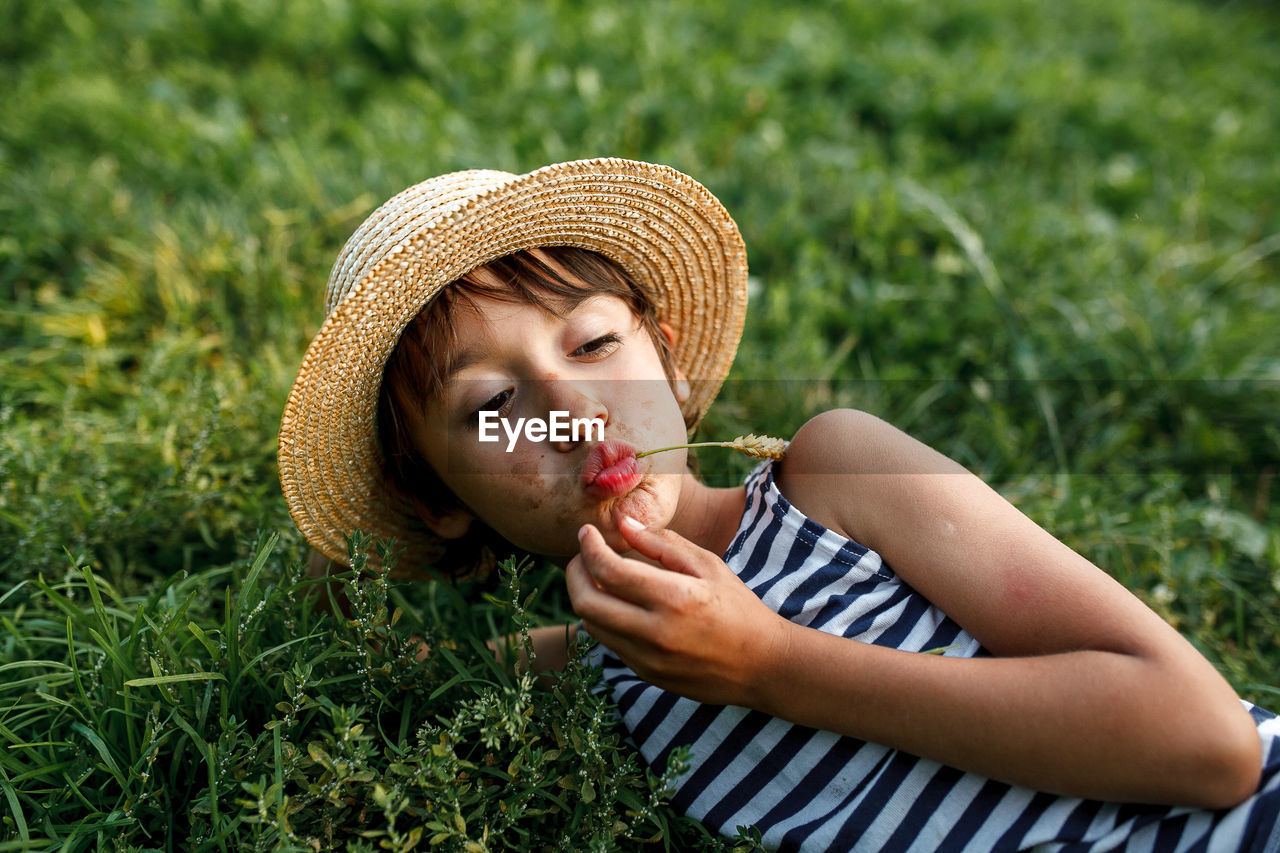 Teenage boy making face while lying on grass outdoors