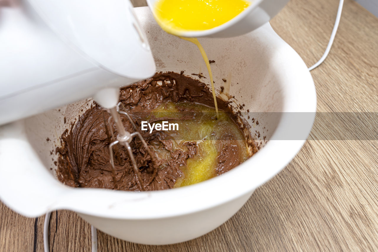 Mixing the dough with a hand mixer with a whisk with melted butter added, the dough is thick mass.