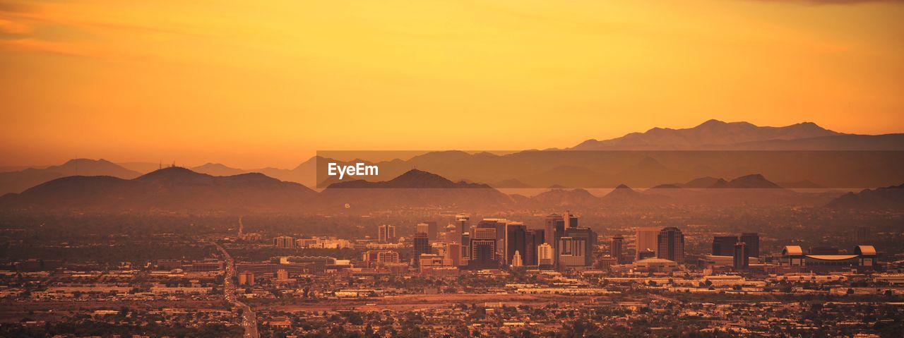 Illuminated cityscape against sky during sunset