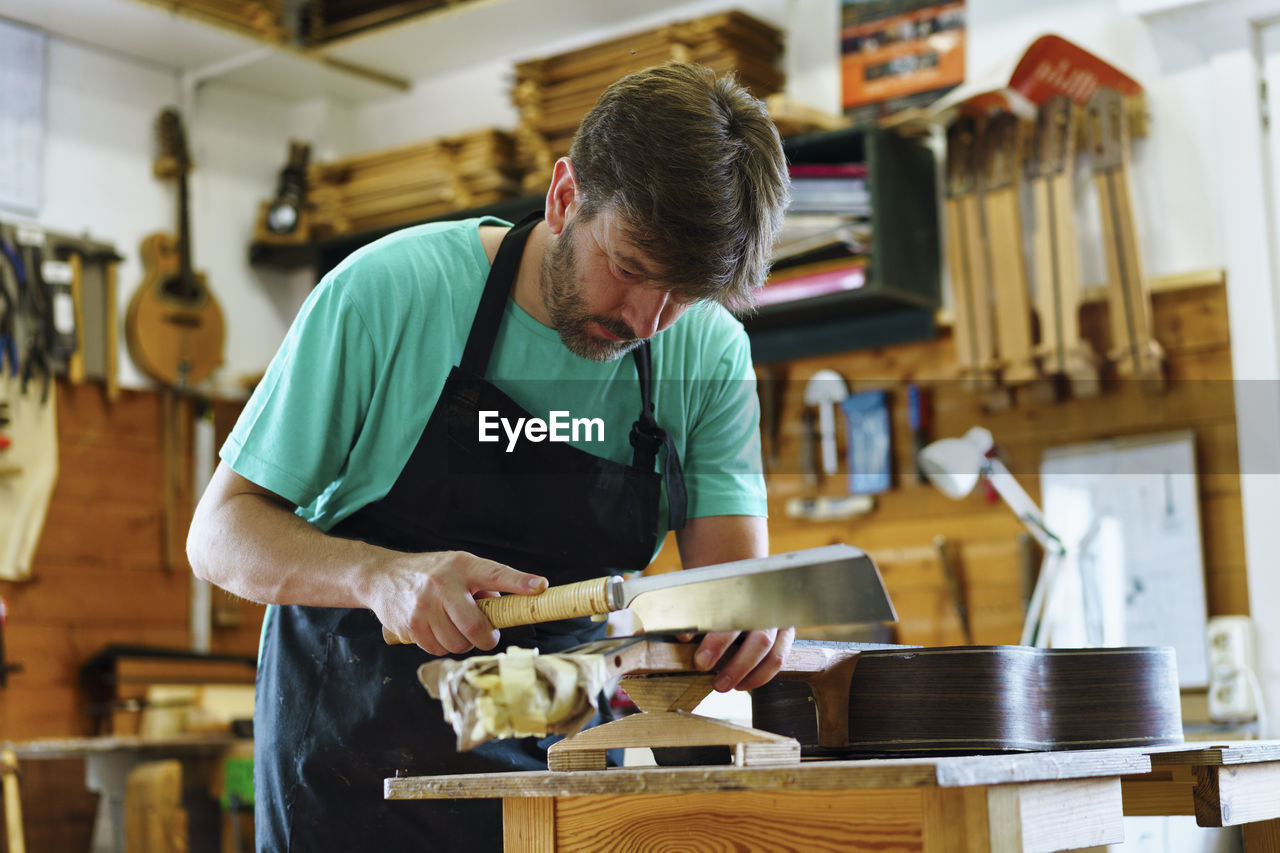 Luthier cutting fretboard on workbench in workshop