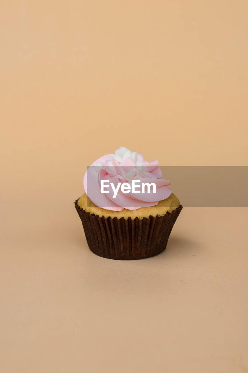 CLOSE-UP OF CUPCAKES ON PINK BACKGROUND
