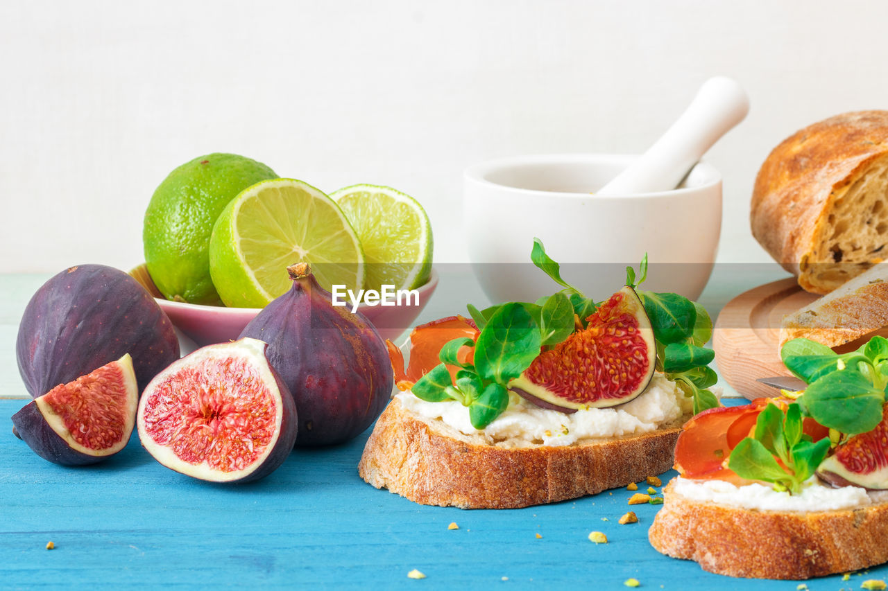 Toast with feta cheese, fresh figs, bacon, fresh leaves of salad and crushed pistachio nuts. 