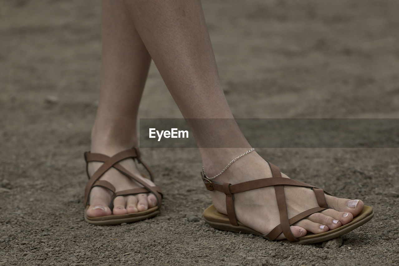 Low section of woman standing on sand