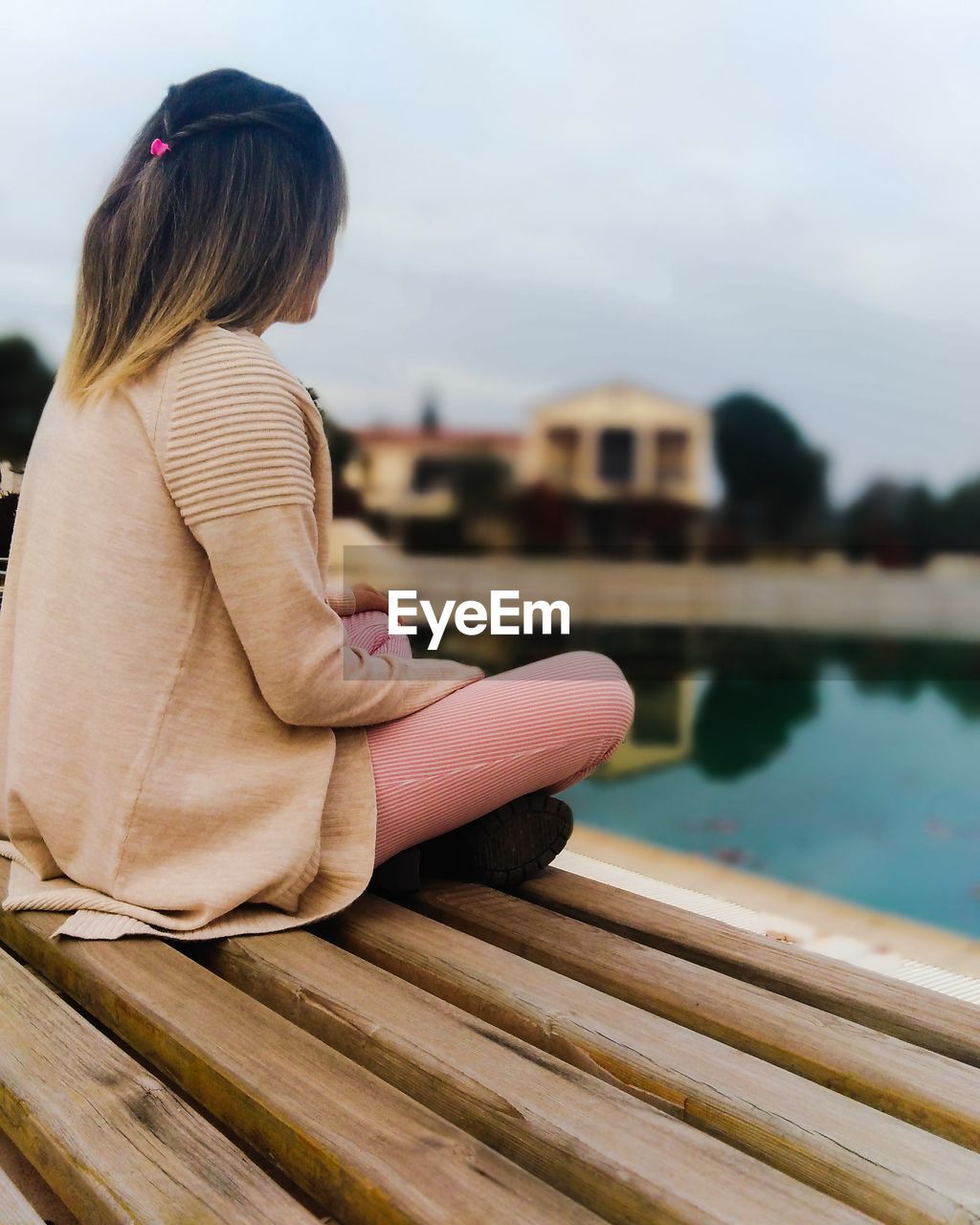 Side view of girl sitting by swimming pool