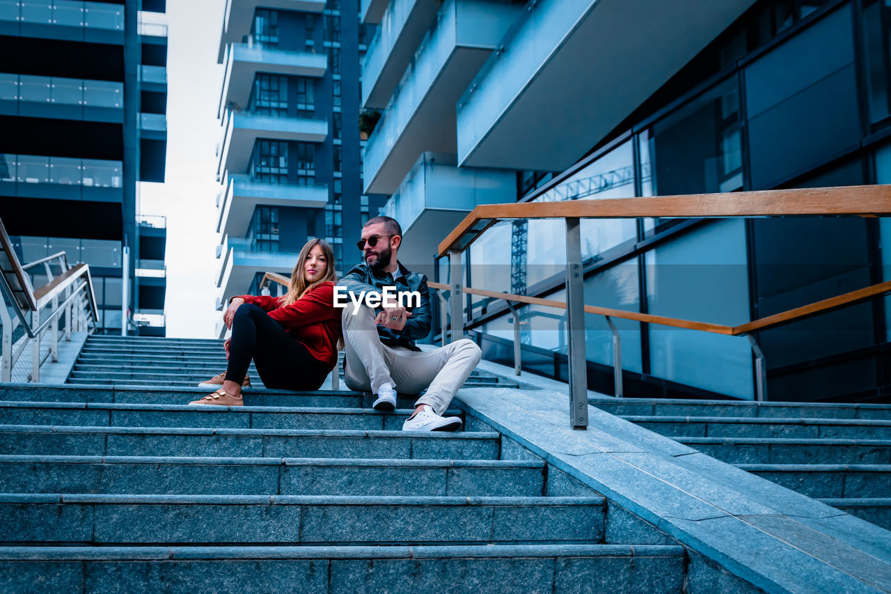 PEOPLE SITTING ON STAIRCASE AT BUILDING
