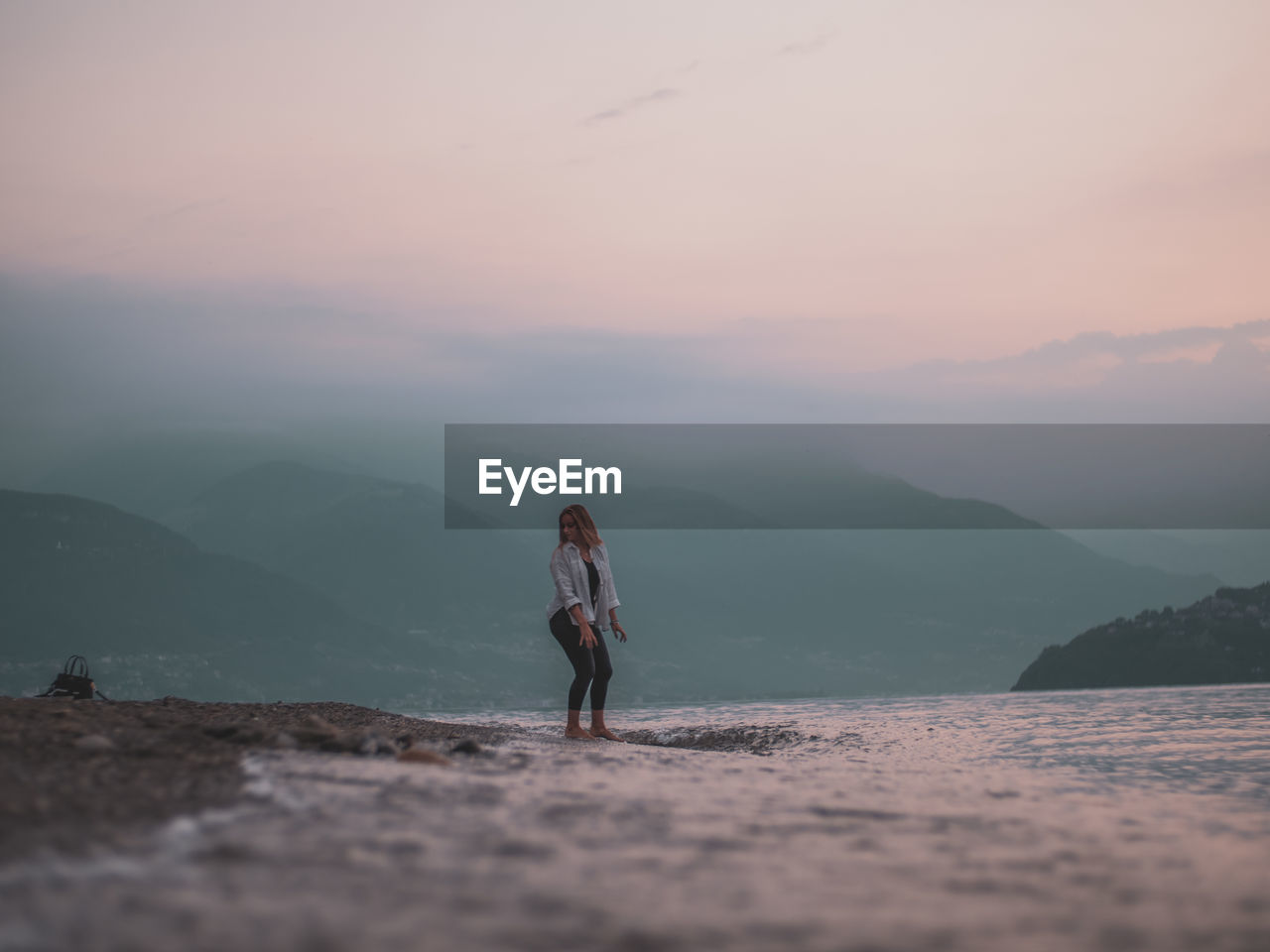 Woman standing on mountain against sky during sunset