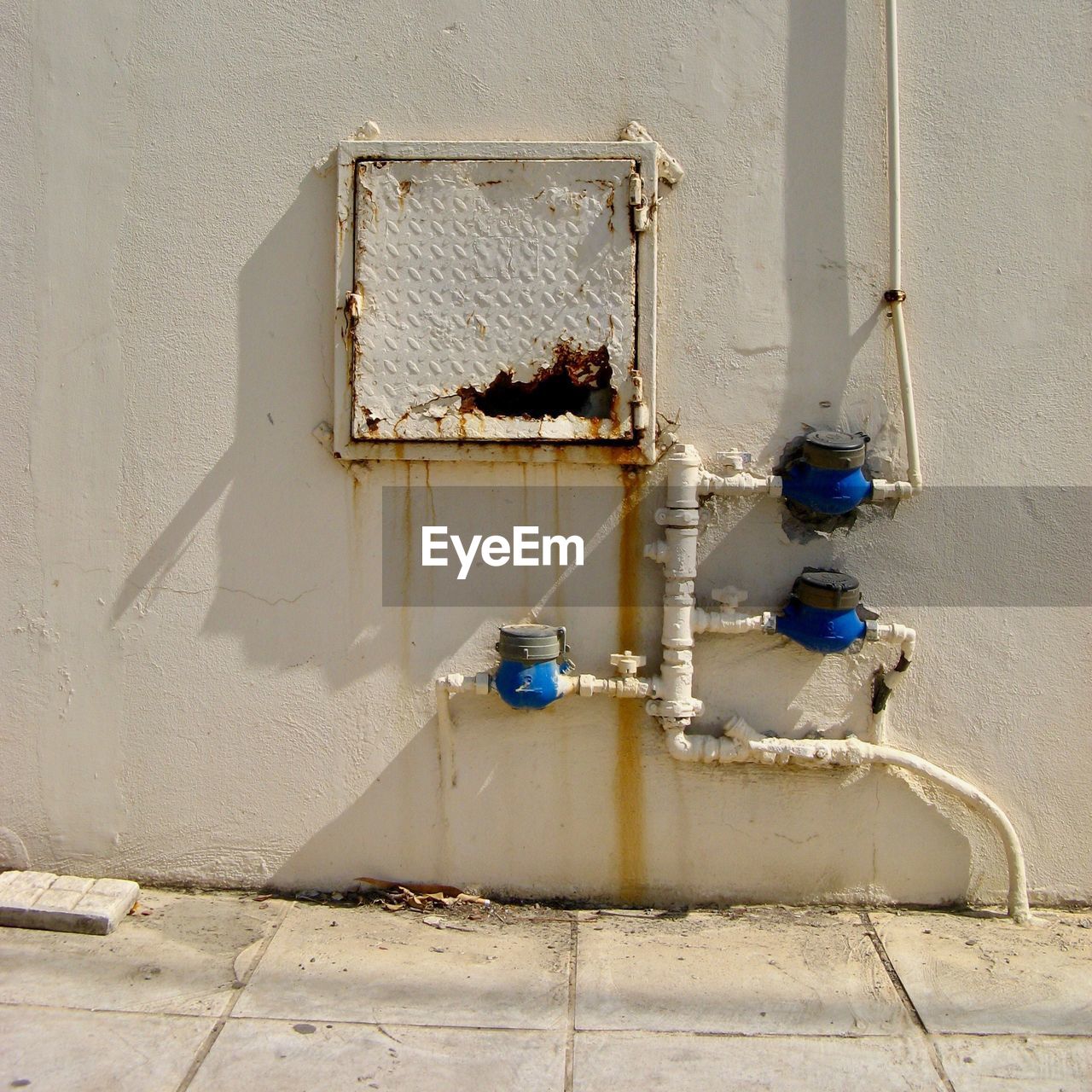 Pipes with water meter by abandoned window on wall