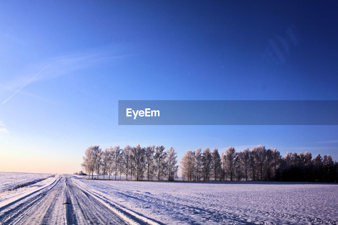 Snow covered street during winter against clear blue sky