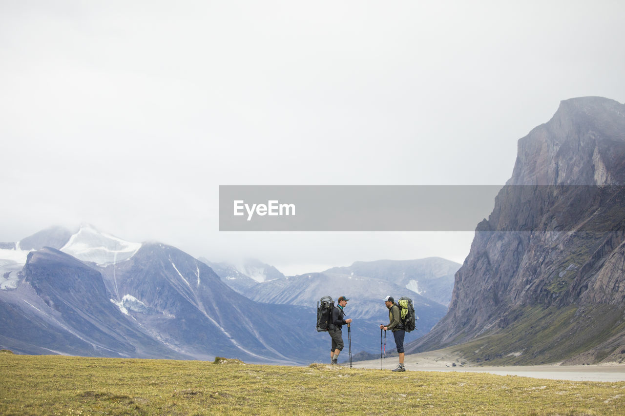 Two friends stop and discuss route during backpacking trip.