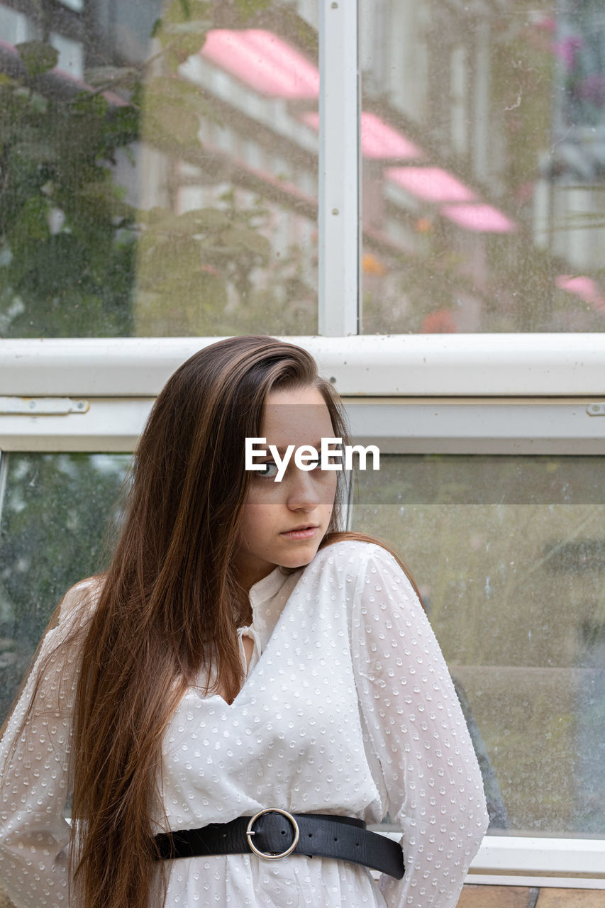 Portrait of young woman looking through window