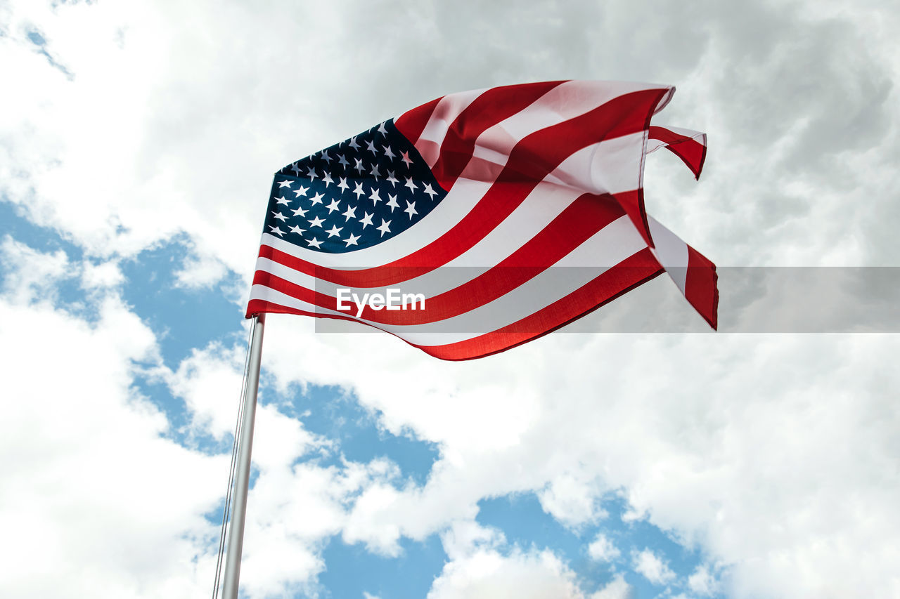 Usa america flag waving in the wind over cloudy sky low angle view.