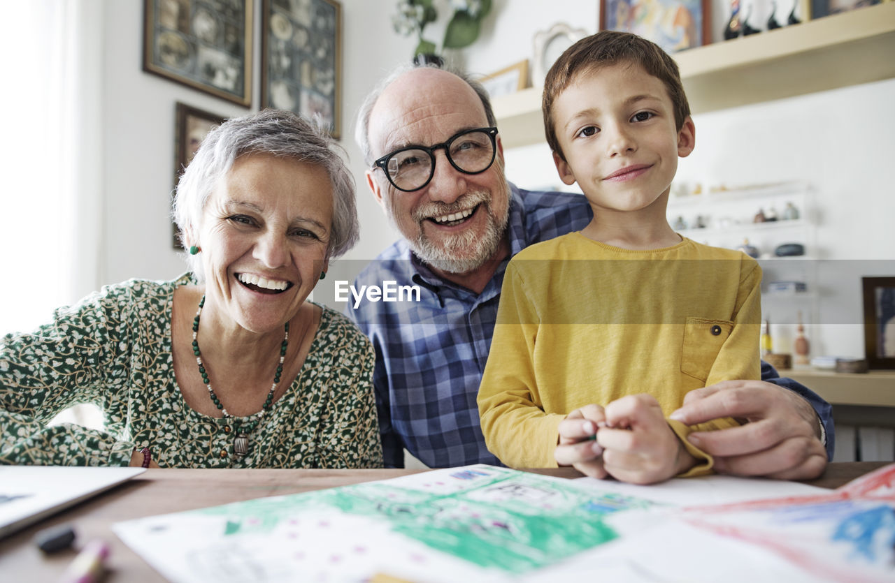 Portrait of happy grandparents with grandson at home