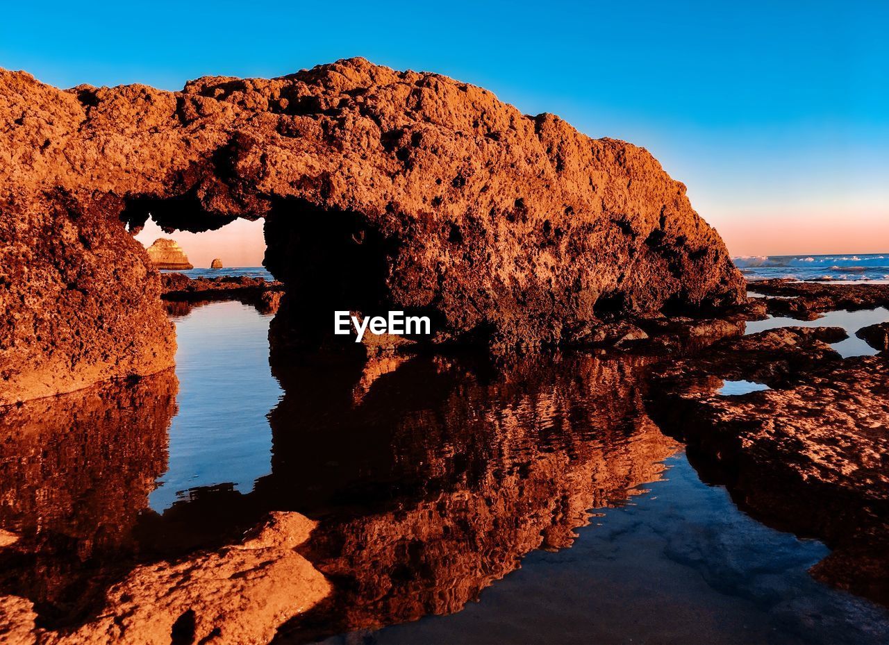 Rock formations by sea against clear sky