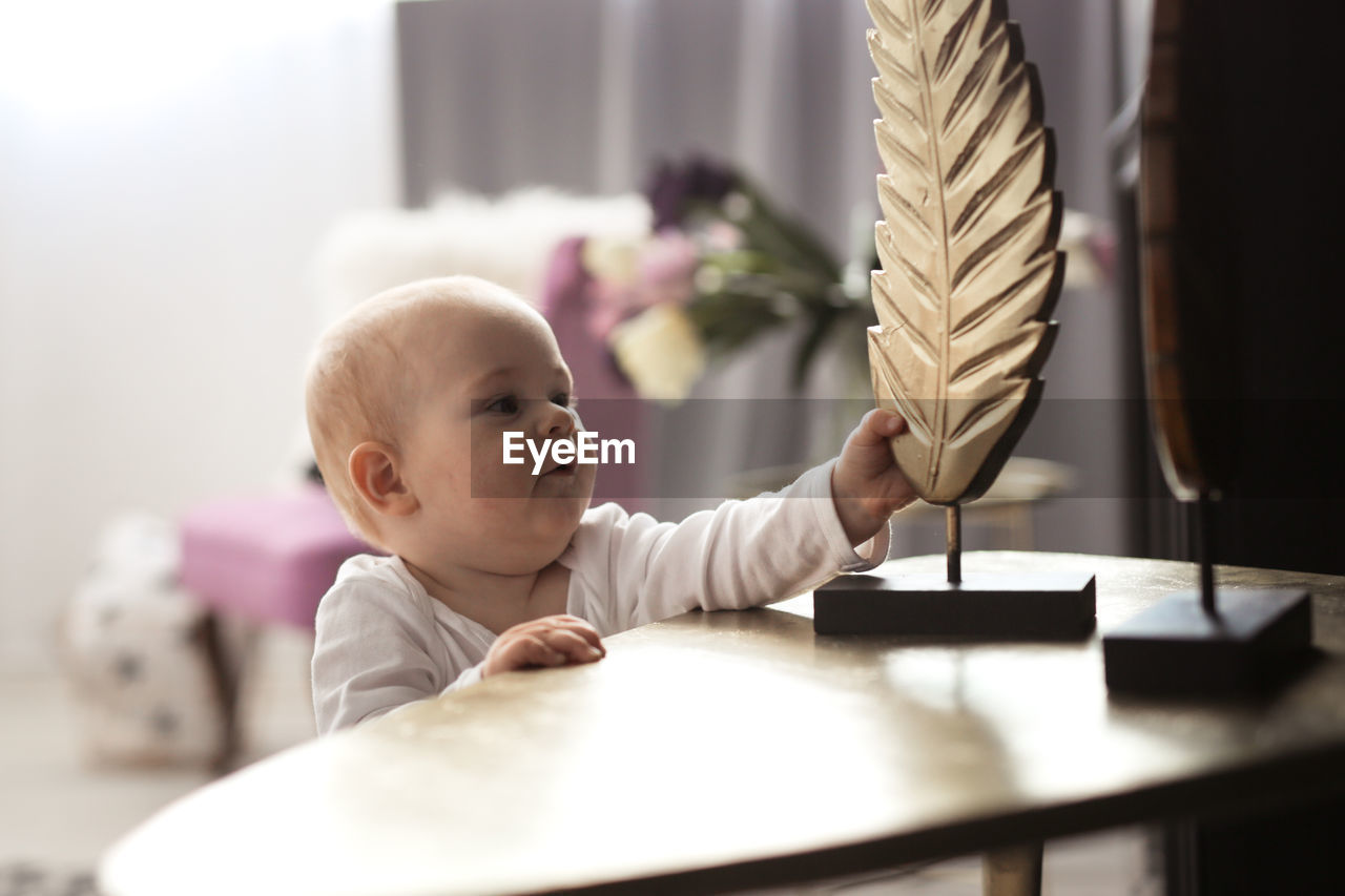 Baby 10 months in real interior, first steps. stretches to the statuette on the table.