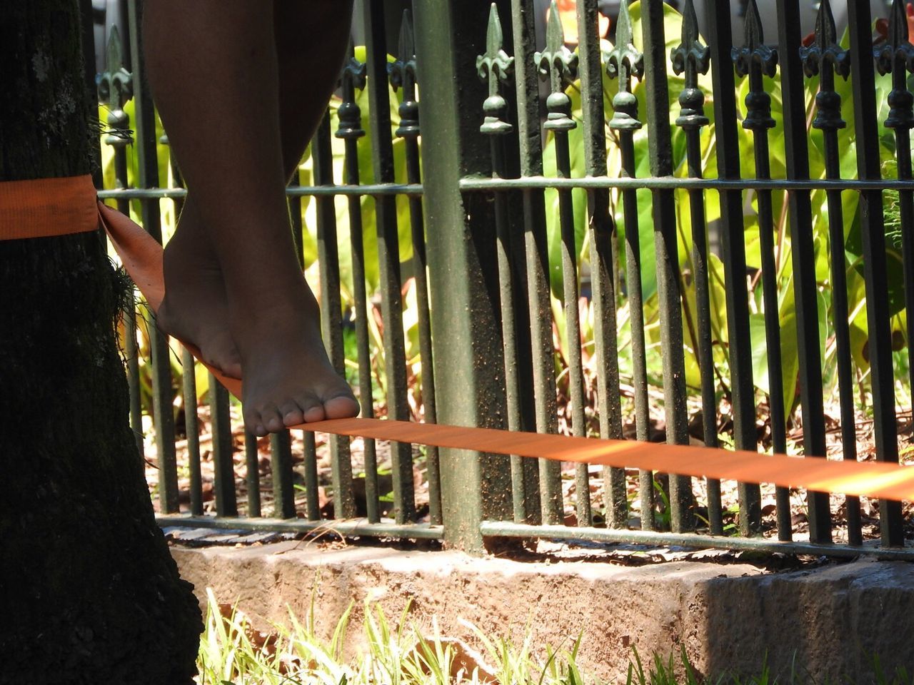 Low section of person balancing on rope by railing