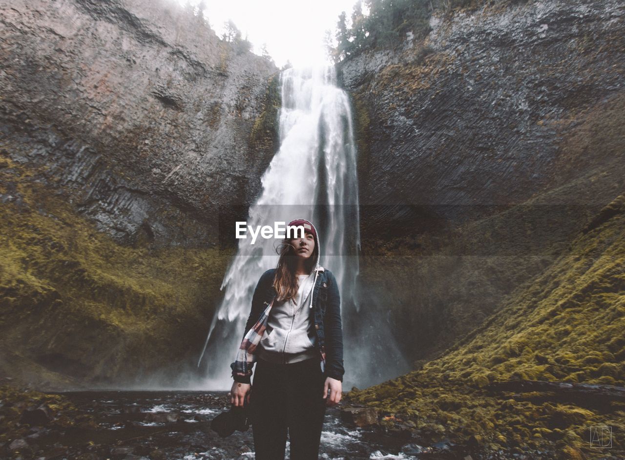 FULL LENGTH PORTRAIT OF YOUNG WOMAN STANDING BY RIVER