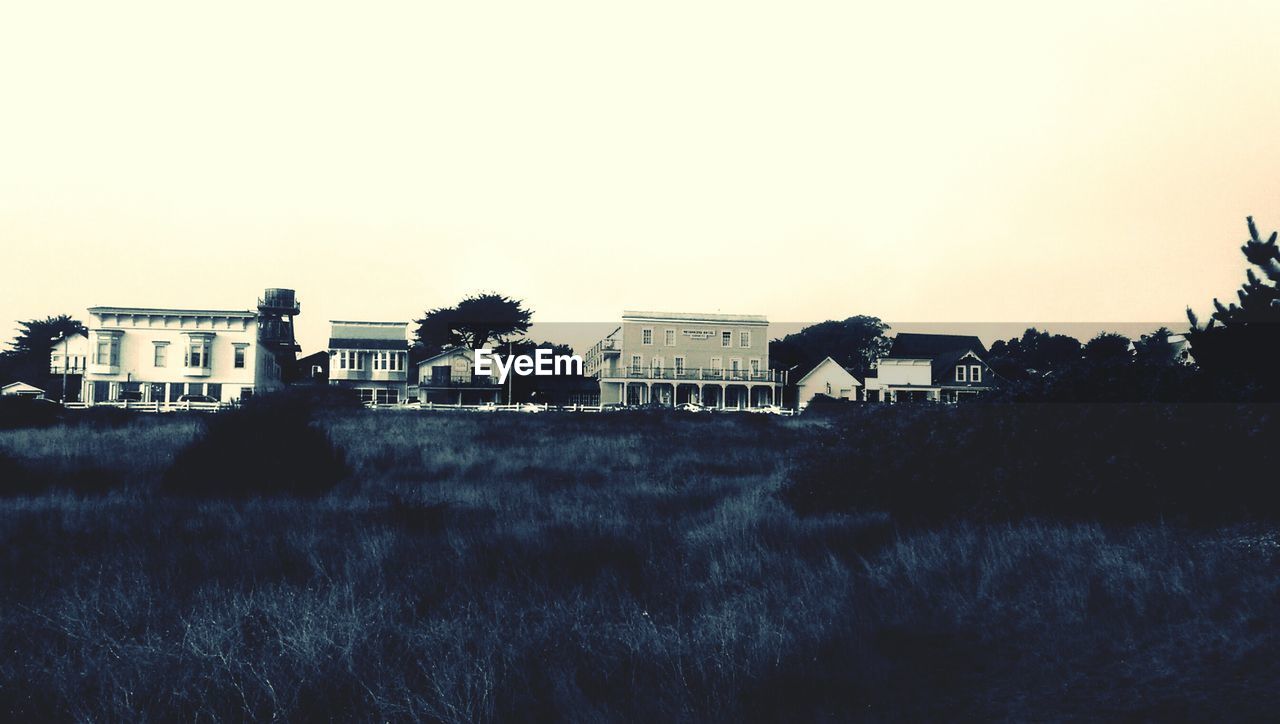 HOUSES ON GRASSY FIELD AGAINST SKY