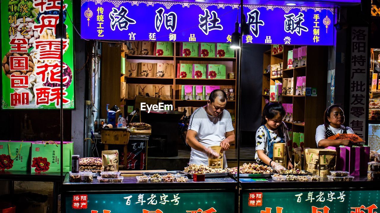 PORTRAIT OF WOMAN STANDING BY STORE