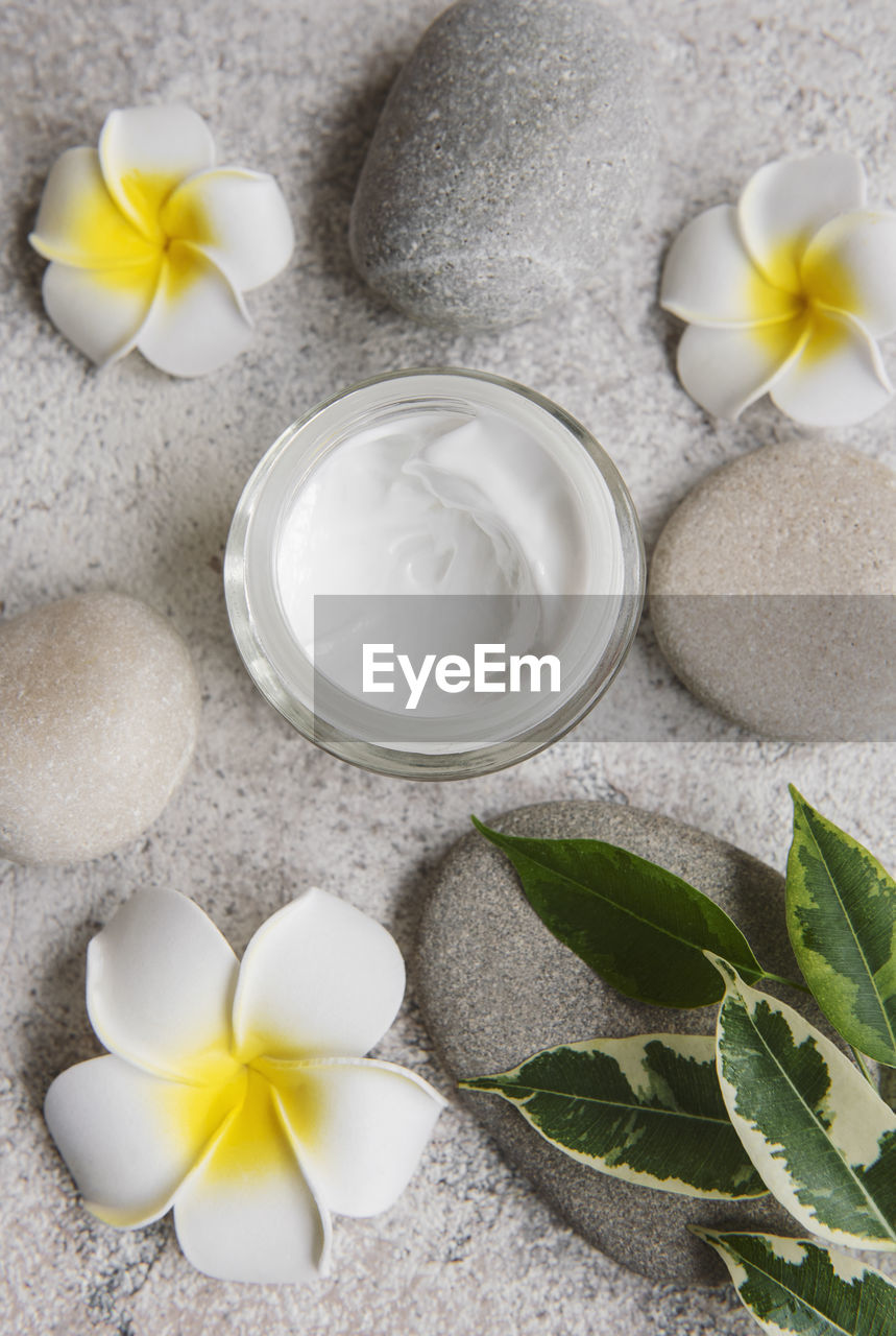 Spa treatment with massage stones and moisturizing cream on gray concrete background