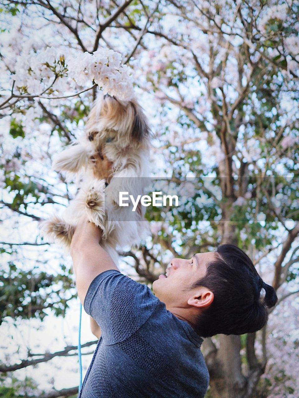 Young holding up dog outdoors