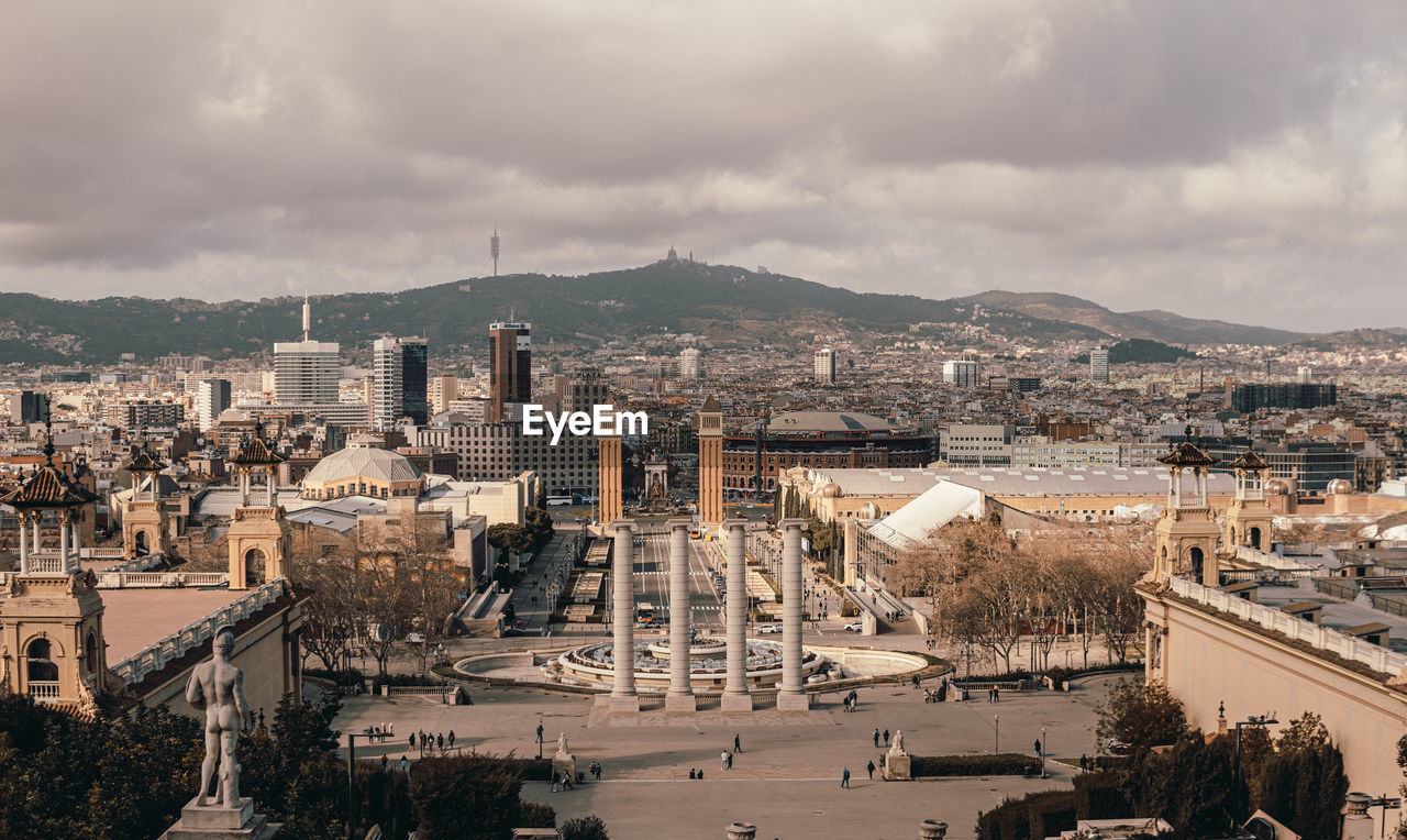 High angle view of city buildings against cloudy sky