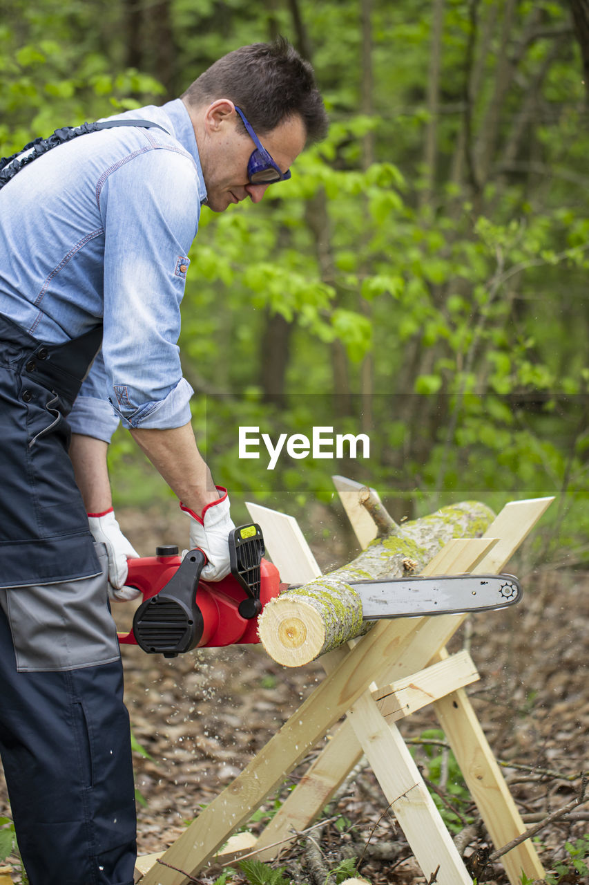 SIDE VIEW OF MAN WORKING ON TREE