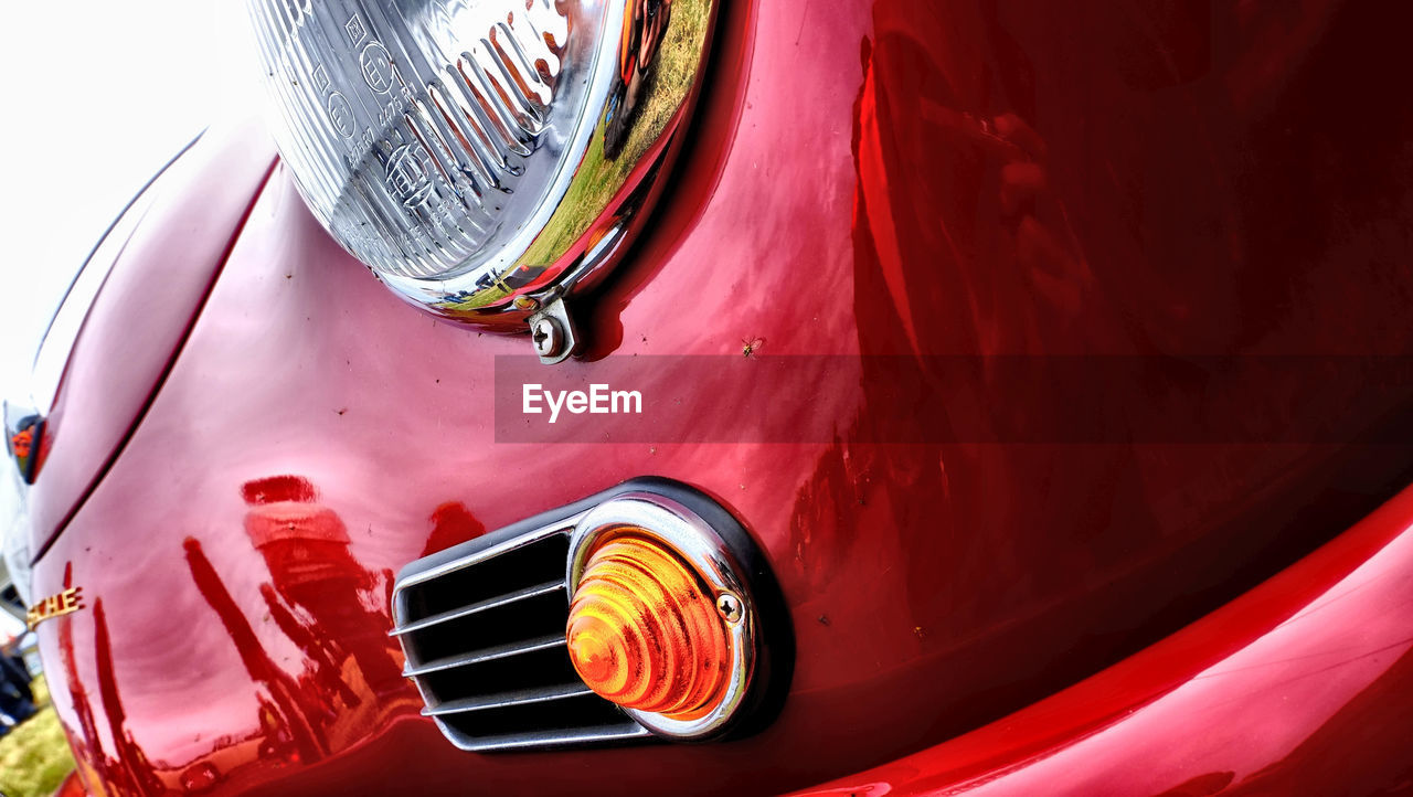 CLOSE-UP OF RED CAR AGAINST BLUE SKY