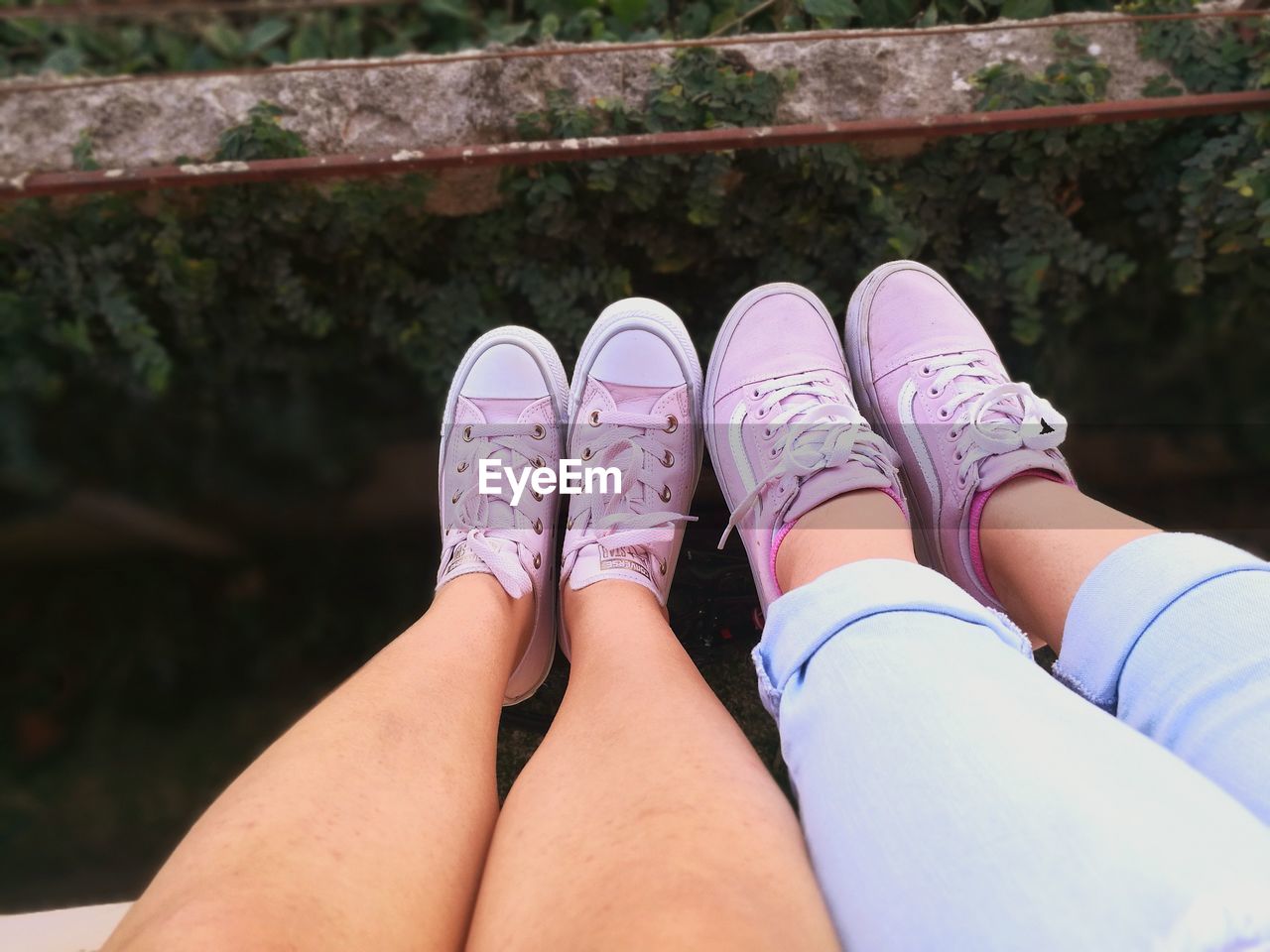 LOW SECTION OF WOMAN SITTING WITH PINK LEGS AND SHOES ON GROUND