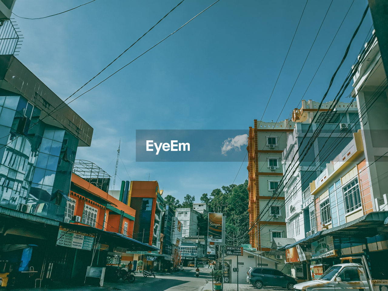 CARS ON ROAD AMIDST BUILDINGS AGAINST SKY