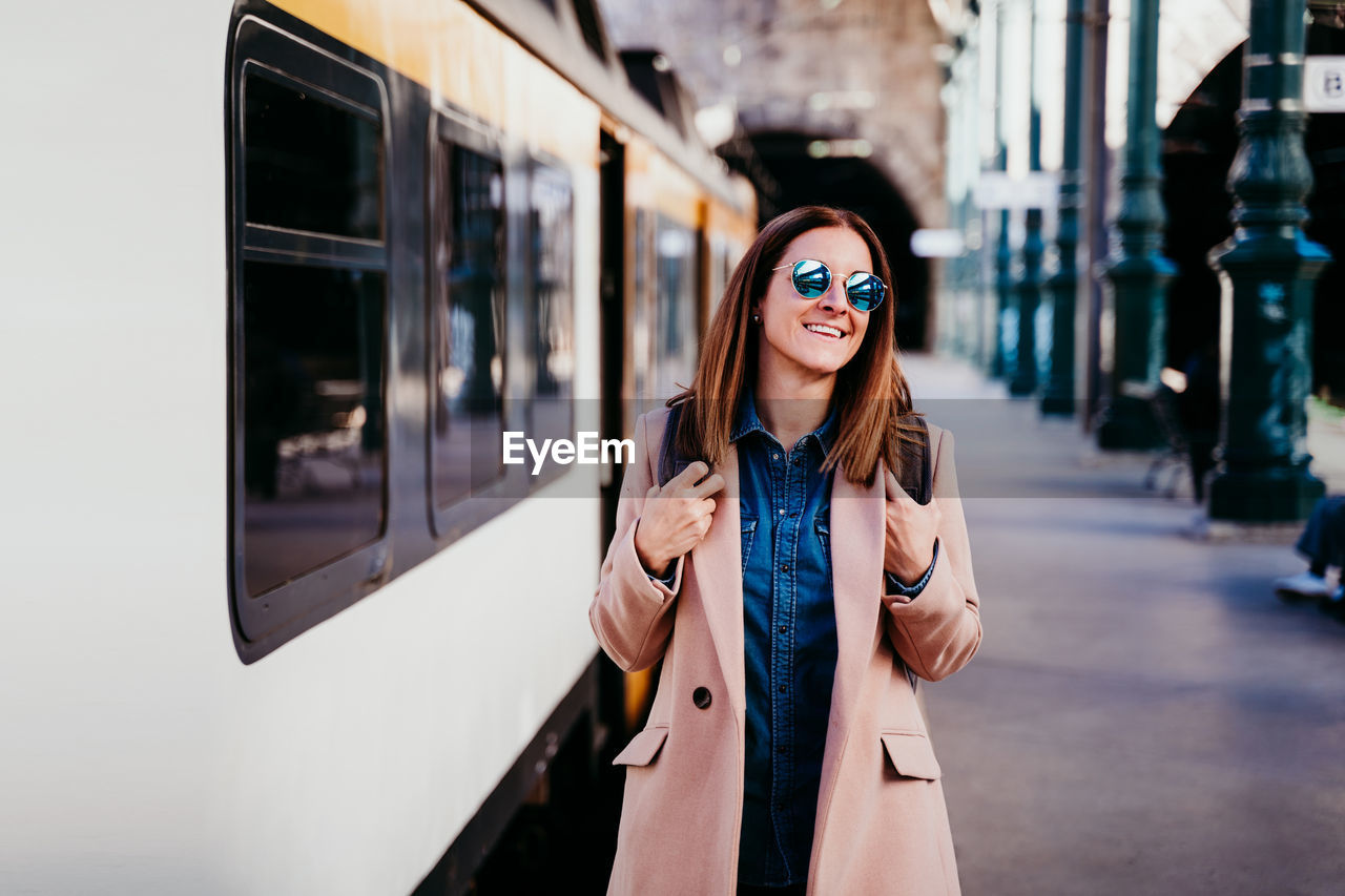 Woman walking by train on railroad station platform