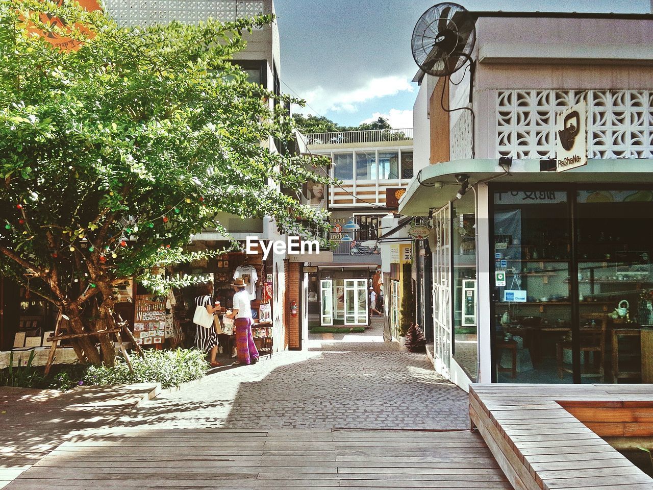 WALKWAY AMIDST BUILDINGS AGAINST SKY