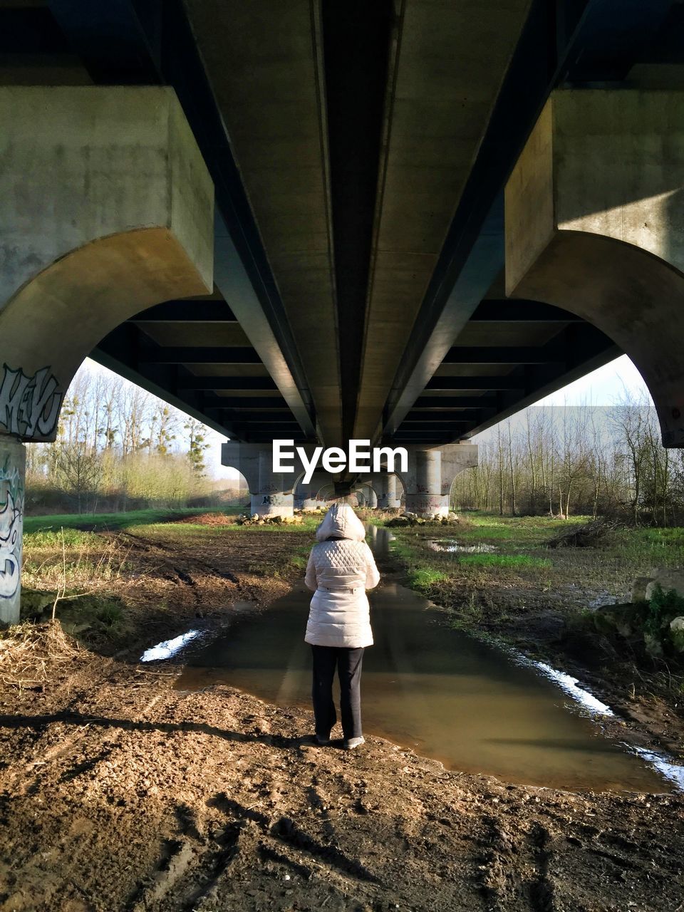 Rear view of woman standing under bridge