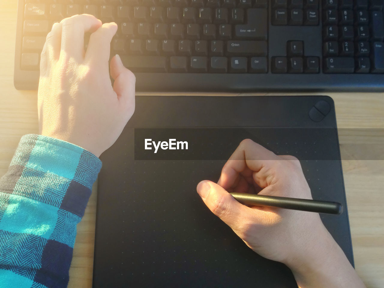 Cropped hands of man using graphic tablet on table