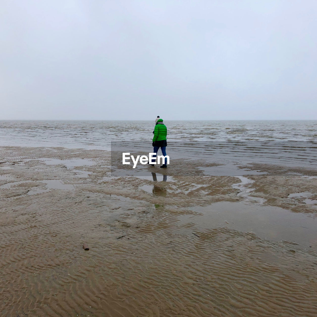 Woman walking at beach against sky