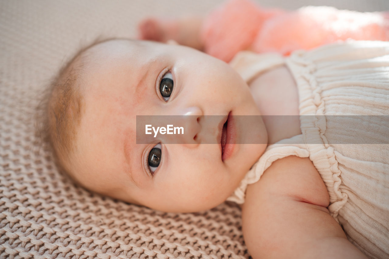 Cute baby girl lying on bed pastel color