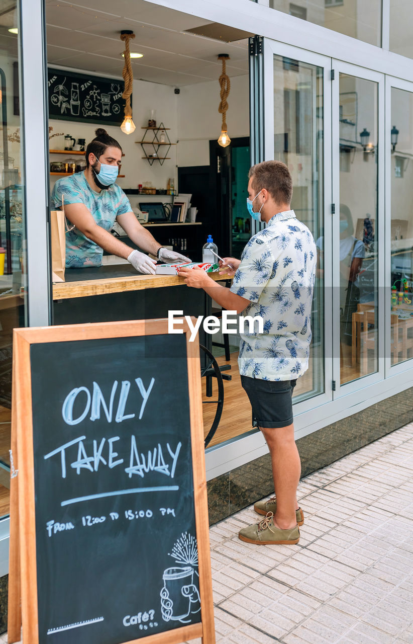 Young man with mask picking up a take away food order