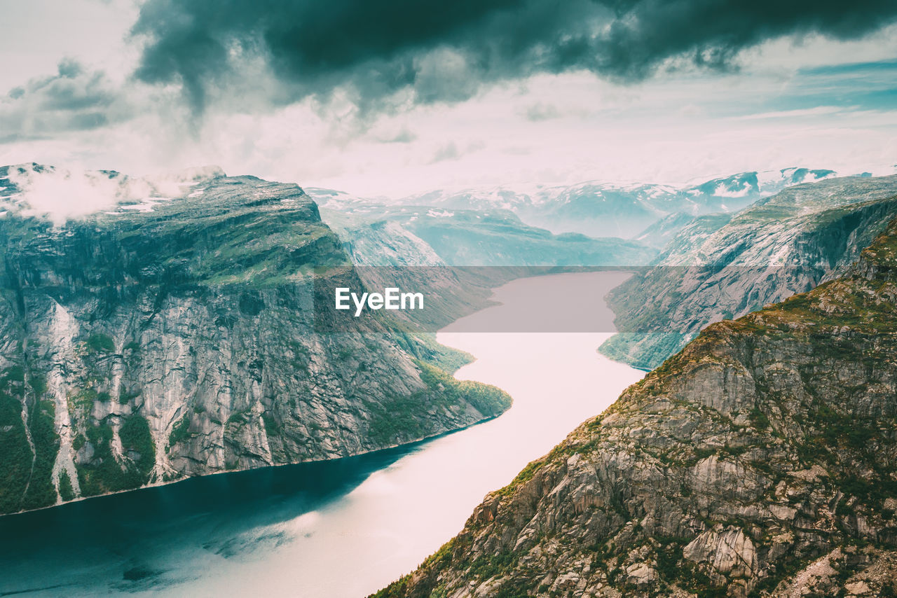 Scenic view of lake amidst snowcapped mountains against cloudy sky