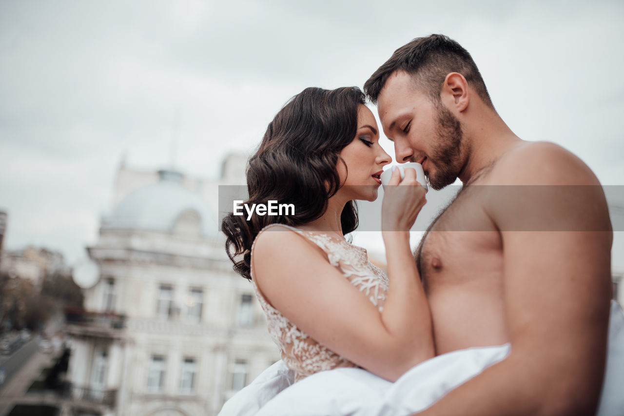 Young couple kissing against clear sky