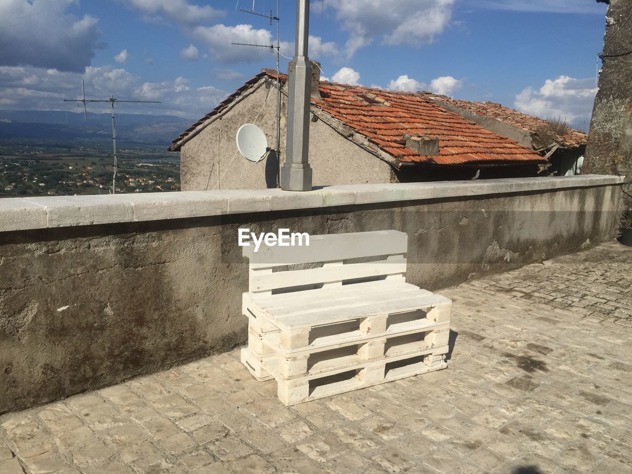 Wooden seat by retaining wall on building terrace