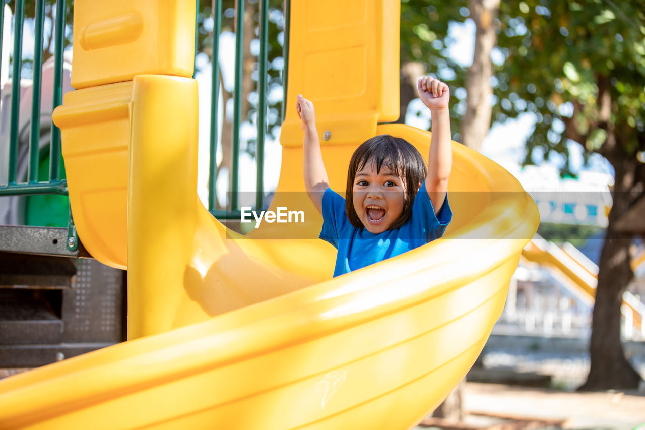 portrait of young woman sitting on slide at playground